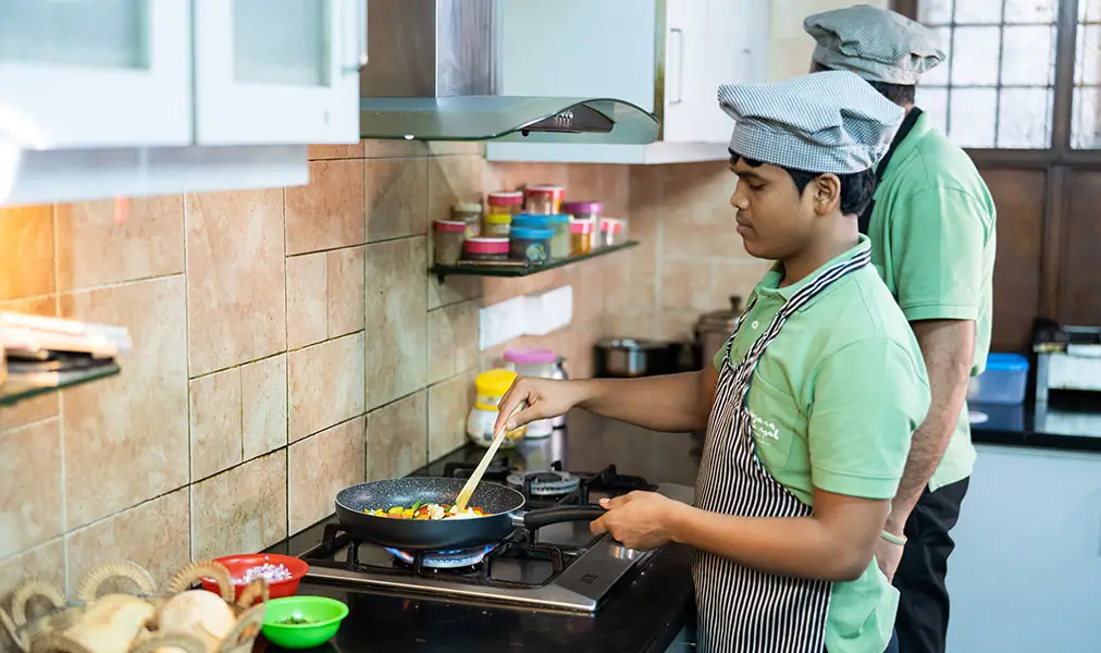 Chef preparing fresh meals in the kitchen at Aashyana Lakhanpal showing in house cooking for guests